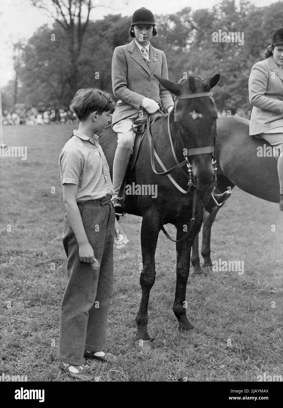 Königliche Konkurrenten auf der Iver Horse Show -- der Herzog von Kent präsentiert seiner Schwester Prinzessin Alexandra eine Rosette. Prinzessin Alexandra, Tochter der Herzogin von Kent, nahm gestern an der Iver (Bucks) Horse Show und Gymkhana Teil. Die Herzogin und der junge Herzog waren bei der Show anwesend. 19. April 1949. (Foto von Fox) Stockfoto