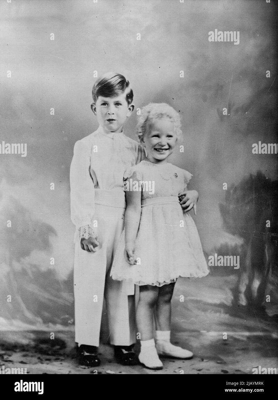 Prinzessin Anne ist drei heute – Eine charmante Studie, die speziell für den Geburtstag von Prinzessin Anne angefertigt wurde, über die Prinzessin mit ihrem Bruder Prinz Charles. Die Prinzessin trägt das Kleid, das sie am Krönungstag trug, von cremefarbener französischer Nadellaufspitze über Chiffon und Taft. Die Halskette, die sie ihrer Mutter, Ihrer Majestät der Königin, geliehen hat, besteht aus acht echten Perlen auf einer Platinkette, und die Brosche, die sie trägt, ist ein Kreis aus Rubinen und Diamanten. (Diese Brosche wurde der Königin als Kind von Königin Maria gegeben). Prinz Charles trägt auch seine Krönungs-Tageskleidung, die Cream serge-Hose Stockfoto