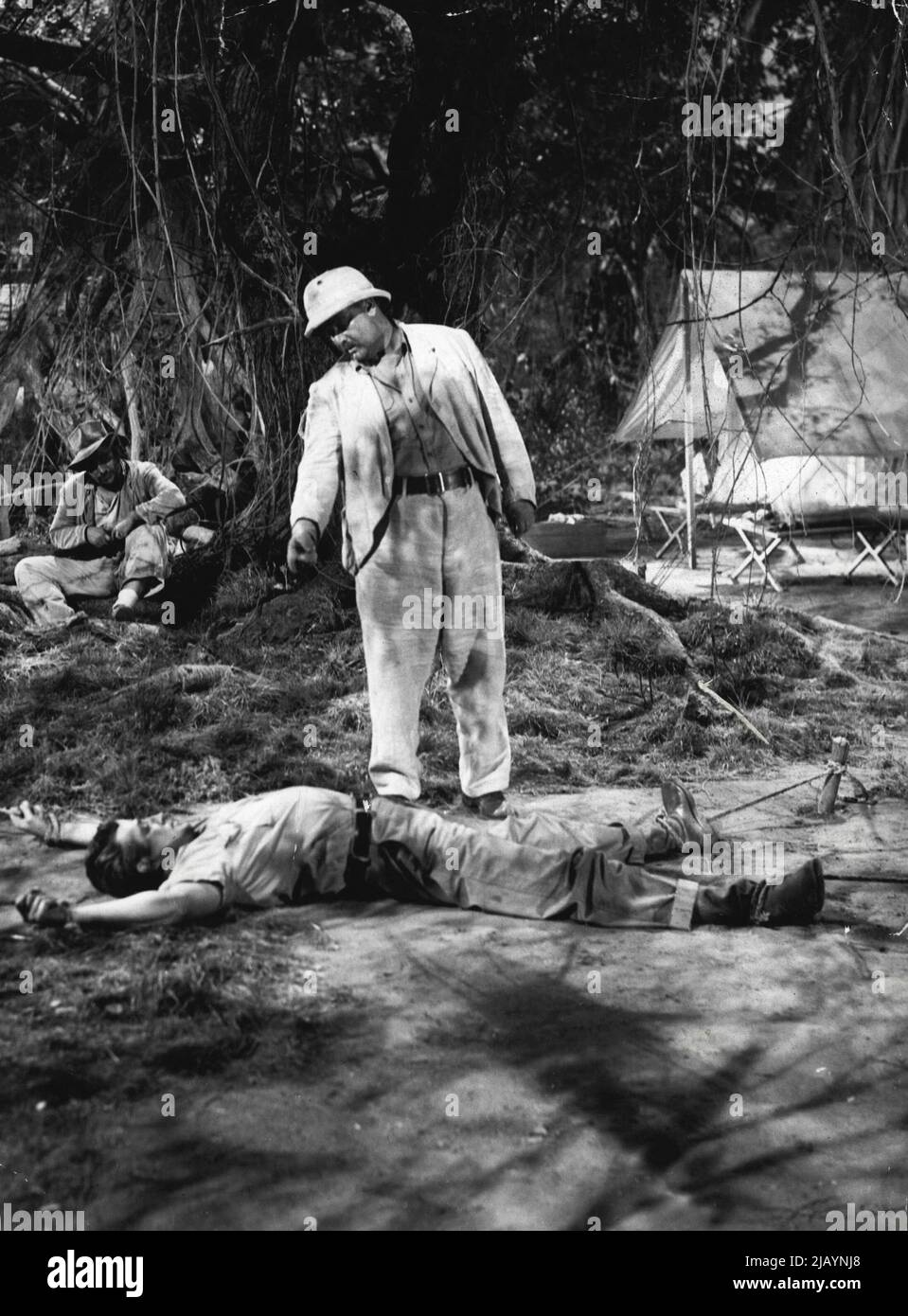 Unterdessen organisiert Huysman, der Niederländer, eine Party, die das Gold mit Gewalt abnimmt. Als seine Raider das Gebiet betreten, werden sie von Bakuba-Wachen entdeckt und Lonni geht hinaus, um sie wegzuschicken und damit Bakuba Leben zu ersparen. Huysmans Partei greift Lonni an und er ist am Boden ausgebreitet, sein Körper ist der gnadenlosen afrikanischen Sonne ausgesetzt. 17. Oktober 1953. Stockfoto