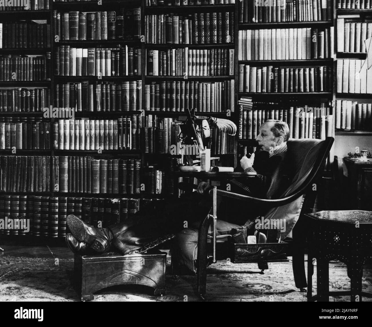 Gadgets, um Komfort beim Lesen zu gewährleisten, umgeben Jack N. Roeg in seiner London Library. Der pensionierte Diamantenhändler besaß einst 22.000 Bücher, ist nun aber mit 3.000 zufrieden. Mit den Gadgets, die er erfunden hat, ist er versichert, dass er nach einer Sitzung in seiner Bibliothek keine schmerzenden Arme, müde Augen oder steife Gelenke geben wird. 19. März 1948. (Foto von Acme). Stockfoto