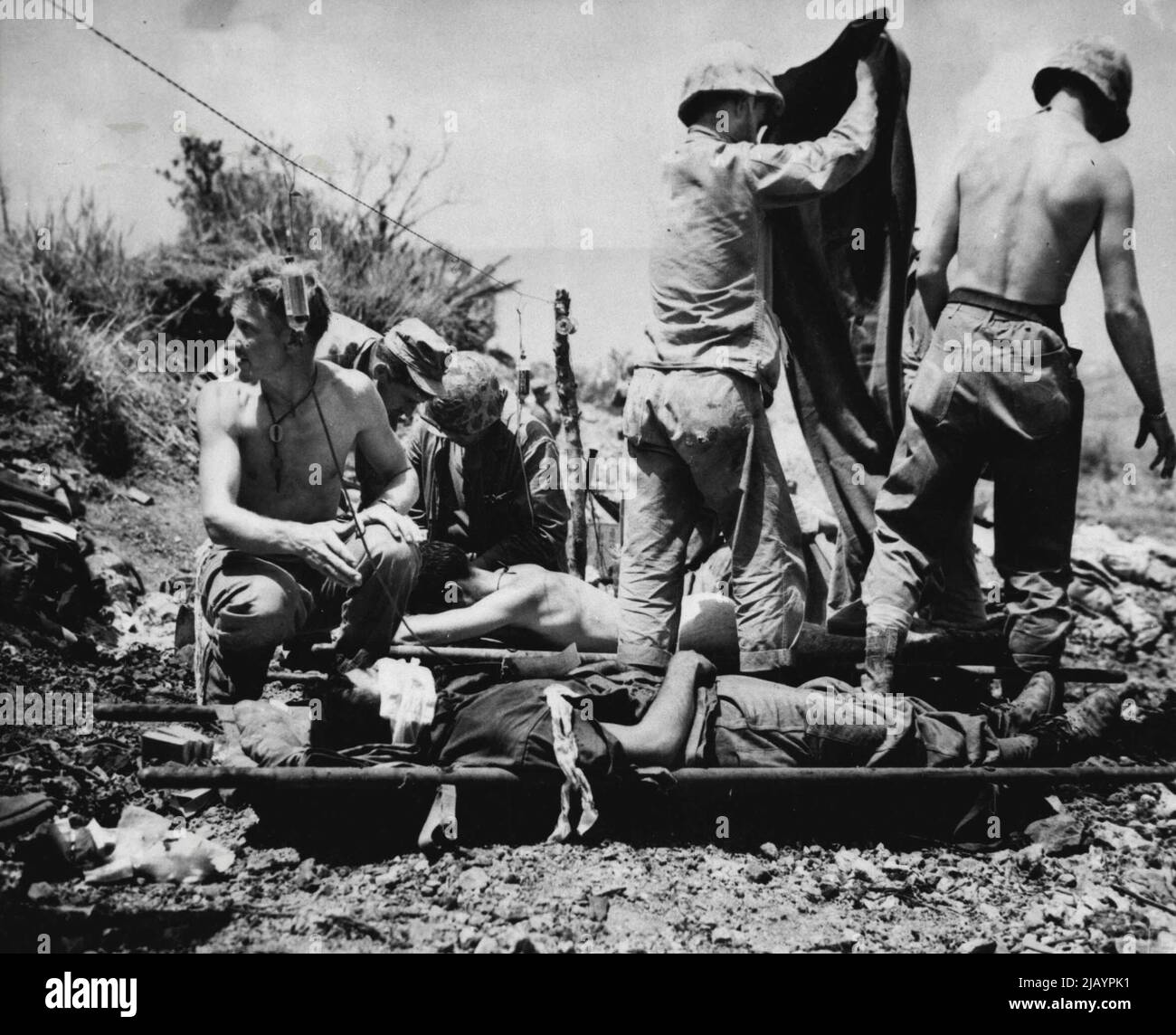 Hilfe für Verwundete auf Okinawa -- Verwundete Truppen auf Okinawa erhalten erste Hilfe an einer Vorwärtsstation. Korpsmänner haben einen Draht aufgereiht, um Blutplasmaflaschen zu halten. 30.Mai 1945. (Foto von Associated Press Photo). Stockfoto