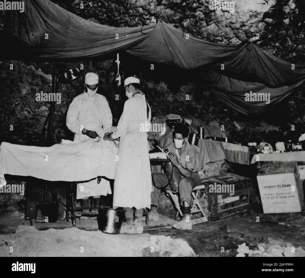 Captured Cave, die als bombensichere Chirurgie verwendet wird -- von links nach rechts, LT. Commander Robert J. Crawley, USNR, aus New Orleans, La., verantwortl. Chirurg; LT. (jg) Julius H. Dietz, aus New York City; PhMI/c Roland M. Anderson, Duluth, Minn, Verabreichung von Betäubungs während einer Bauchoperation. Diese Höhle, die den Japs entnommen wurde, bietet Chirurgen relative Sicherheit und Ruhe, die viele heikle Operationen an Opfern im Kampf durchführen, während der Kampf um Okinawa um sie herum tobt. 20. Juni 1945. (Foto vom offiziellen US Marine Corps Photo). Stockfoto