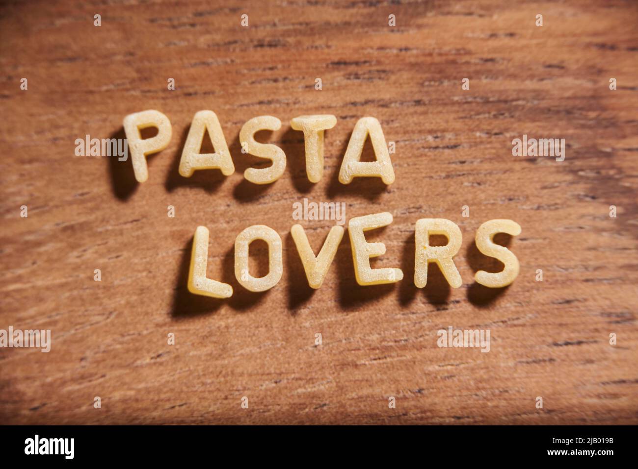 Text Pasta-Liebhaber mit Alphabet Suppe Pasta Buchstaben auf einem hölzernen Hintergrund gebildet. Stockfoto