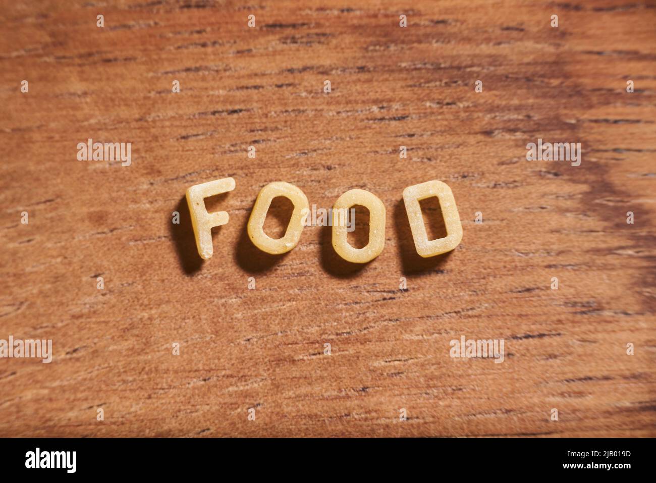 Word Food mit Alphabet Suppe Pasta Buchstaben auf einem hölzernen Hintergrund gebildet. Konzept: Spaß mit Essen Stockfoto