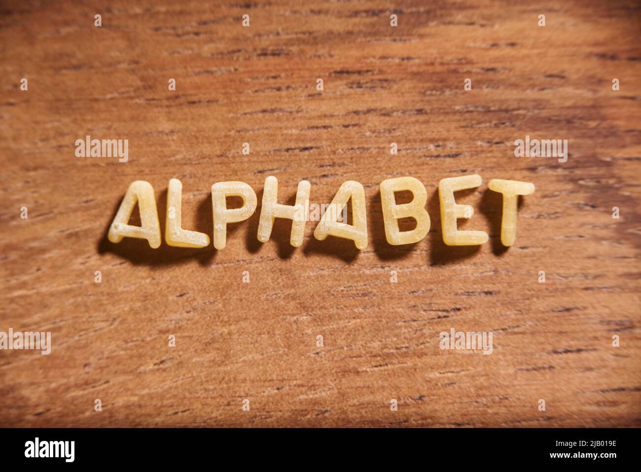 Wort-Alphabet mit Suppenpasta Buchstaben auf einem hölzernen Hintergrund gebildet. Konzepte von Nahrung und Bildung. Stockfoto