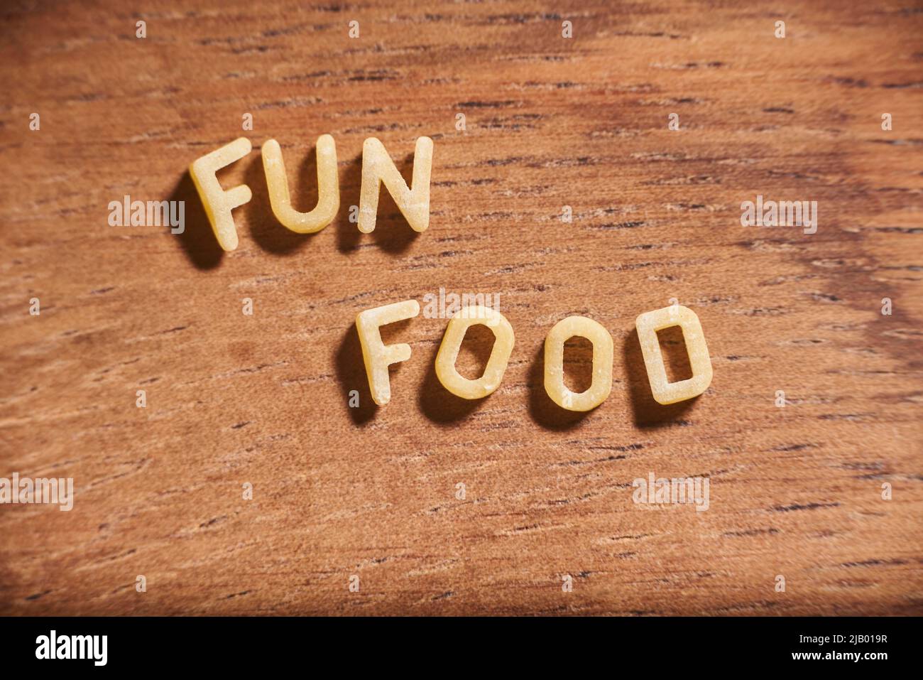 Text Fun Food mit Alphabet Suppe Pasta Buchstaben auf einem hölzernen Hintergrund gebildet. Stockfoto