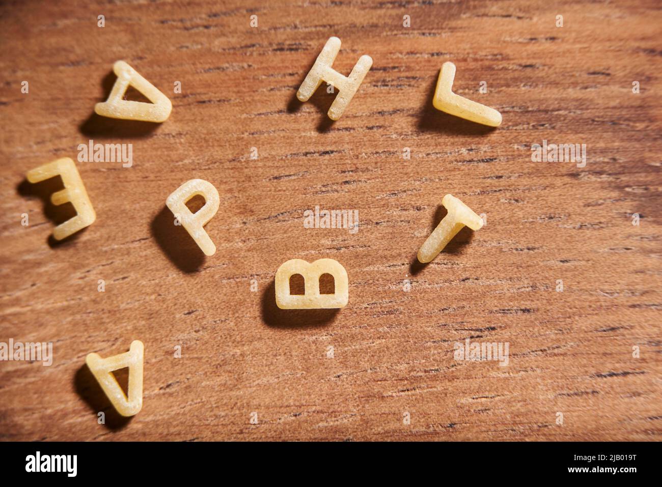 Buchstaben des Alphabets Wort aus Suppenteigwaren in Unordnung auf einer hölzernen Oberfläche gelegt gemacht Stockfoto