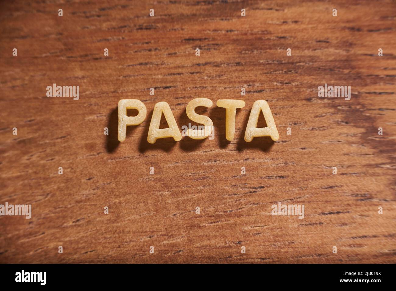 Wort Pasta mit Alphabet Suppe Pasta Buchstaben auf einem hölzernen Hintergrund gebildet. Konzept: Italienisches Essen Stockfoto
