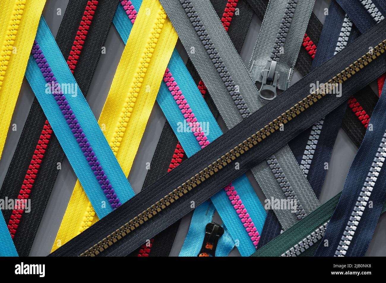 Verschiedene helle Kleiderreißverschlüsse auf dem hellgrauen Tisch im Zimmer Stockfoto