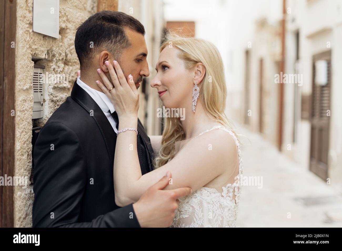 Junges romantisches Paar, blonde Frau und schwarzhaariger Mann, einander anblickend, Braut mit dem Gesicht des Bräutigams. Eid, Versprechen Stockfoto