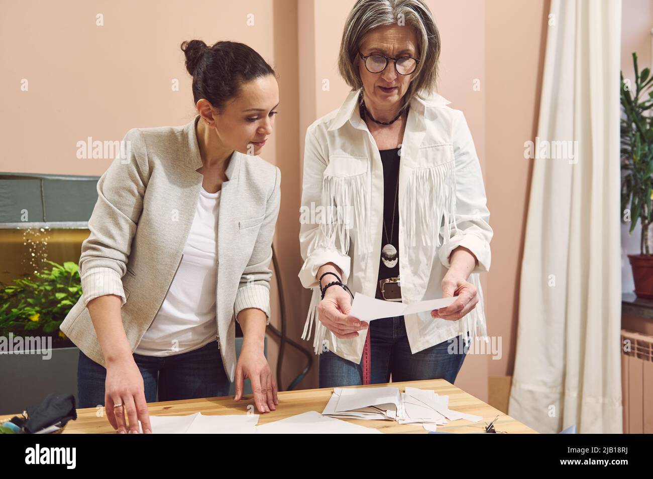 Kreative qualifizierte Team von zwei Frauen Modedesigner Couturiers Schneider sehen Mode Skizze und diskutieren Nähmuster während der Arbeit in modernen c Stockfoto
