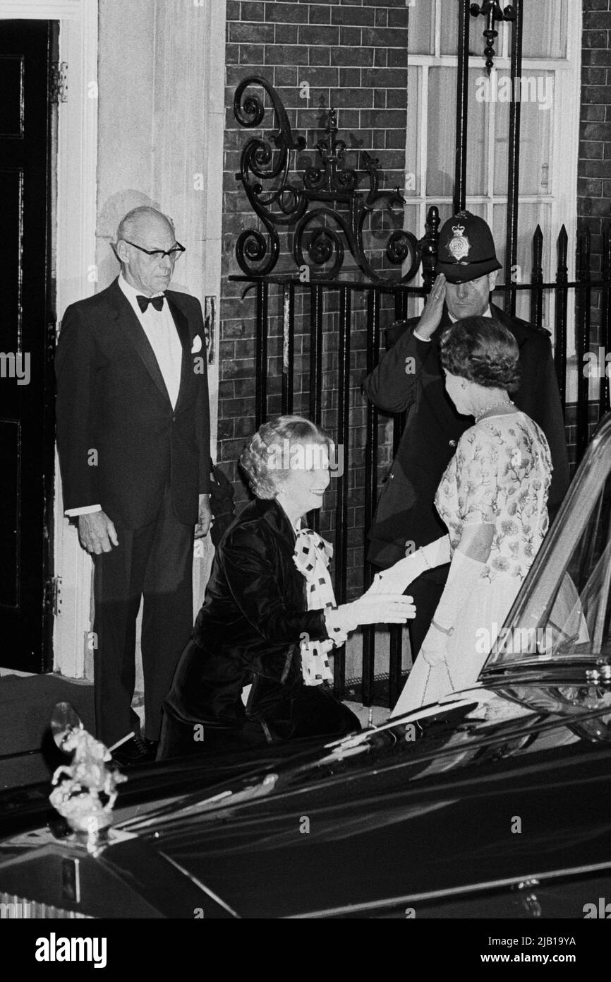 Datei-Foto vom 4/12/1985 von Premierministerin Margaret Thatcher, die Königin Elizabeth II. Kurz vor ihrem Eintreffen zu einem Abendessen in der Downing Street 10, London, anlässlich des 250.. Jahrestages des Amtes des Premierministers. Ehemann Denis Thatcher sieht zu, wie ein Polizist grüßt. Ausgabedatum: Donnerstag, 2. Juni 2022. Stockfoto