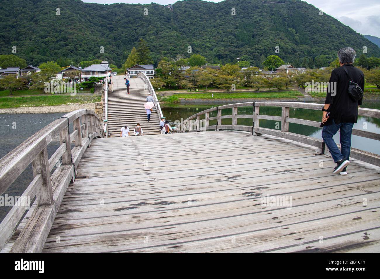 Touristen, die an bewölkten Tagen über die Kintai Bridge (Kintaikyo), eine historische Holzbogenbrücke, wandern. Es wurde 1673 erbaut und erstreckt sich über den Nishiki River Stockfoto