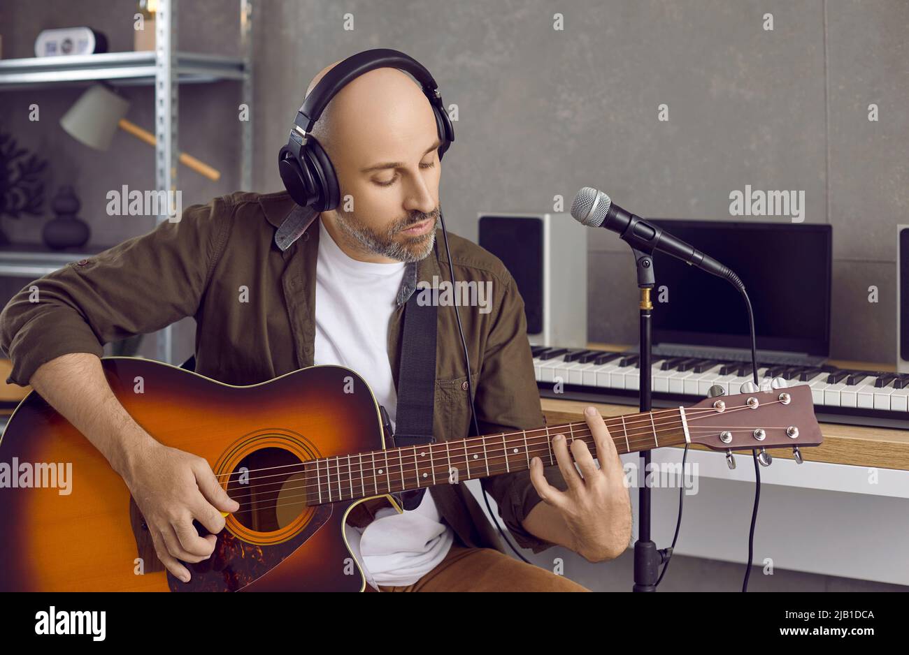 Kaukasischer Mann spielt Gitarre und singt im Mikrofon Stockfoto
