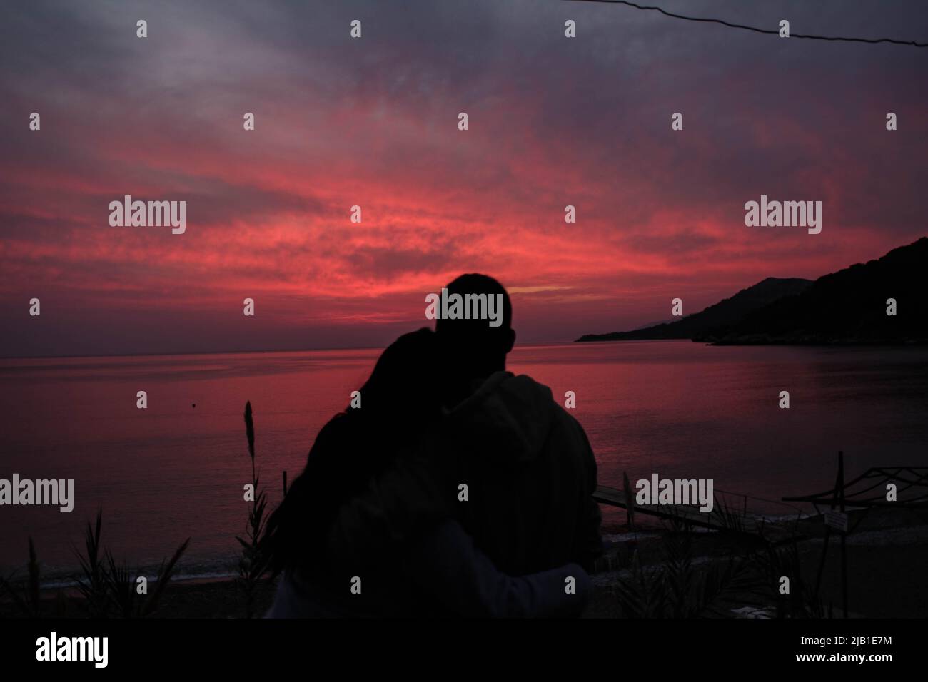 Zwei Liebhaber, die die Sonne am Meer untergehen Stockfoto