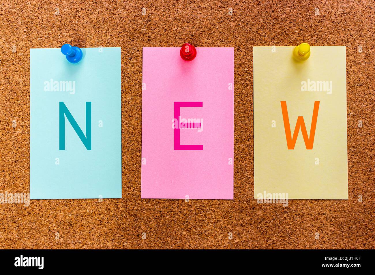 Konzeptionelles 3-Buchstaben-Schlüsselwort NEU auf mehrfarbigen Aufklebern, die an einem Korkbrett angebracht sind. Farbenfrohes, poppiges und ausgefallenes Konzept, das brandneues Ding darstellt. Stockfoto