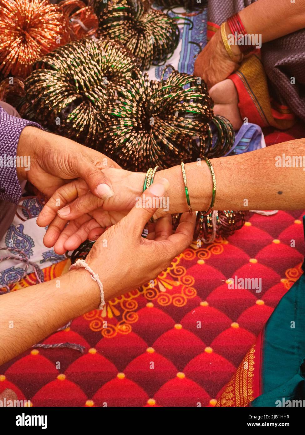 Vor der Trauung eine Dame Armreif Verkäufer setzt grüne Glas Armreifen, indische Kultur. Stockfoto