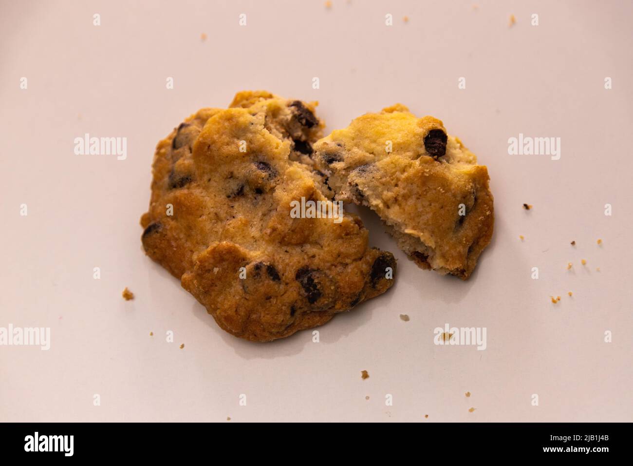 Ein Stück Brot mit kleinen Stücken gesüßter Schokolade auf dem Tisch in rauer Stimmung verschließbar machen. Stockfoto