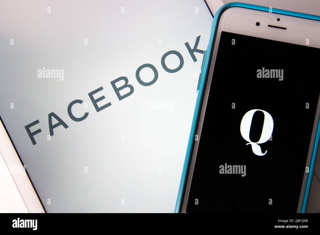 Kumamoto, JAPAN - Okt 20 2020 : das Logo von Qanon, einer rechtsextremen Verschwörungsgruppe, auf dem iPhone mit Facebook-Logo als Hintergrund. Stockfoto