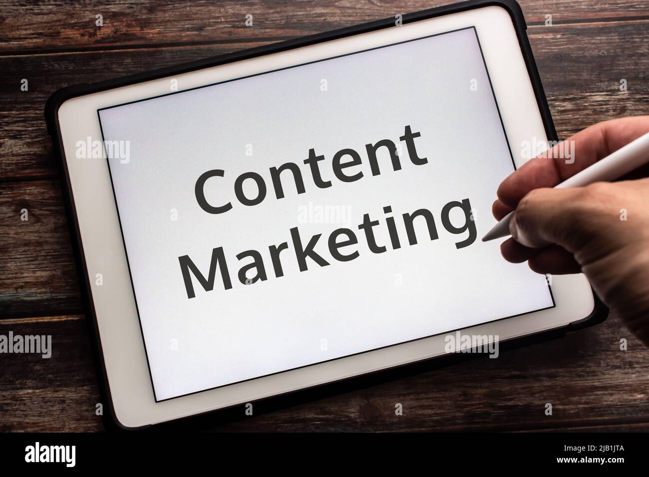 Keyword Content Marketing auf dem Tablet. Eine Marketingstrategie, die sich auf die Erstellung, Veröffentlichung und Verteilung von Inhalten für einen Zielbenutzer konzentriert. Mann mit einem Stift Stockfoto