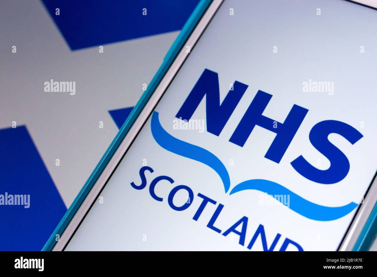 Kumamoto, JAPAN - Sep 6 2021 : Closeup-Logo von NHS Scotland, dem öffentlich finanzierten Gesundheitssystem in Schottland, auf dem iPhone auf schottischer Flagge. Stockfoto