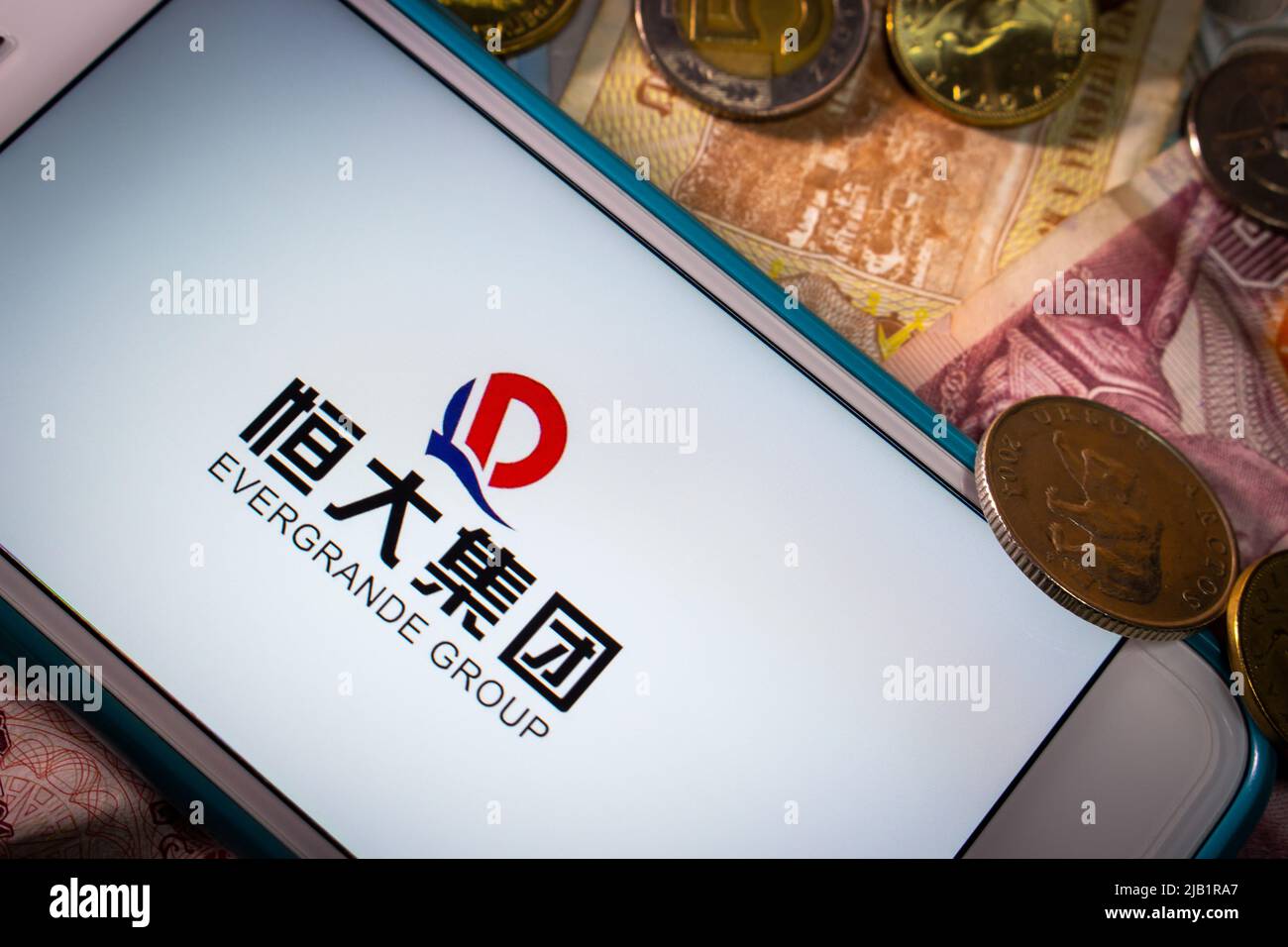 Kumamoto, JAPAN - Sep 23 2021 : die Evergrande Group, Chinas führender größter Immobilienentwickler, auf dem iPhone mit Zufallsmünzen und Banknoten Stockfoto