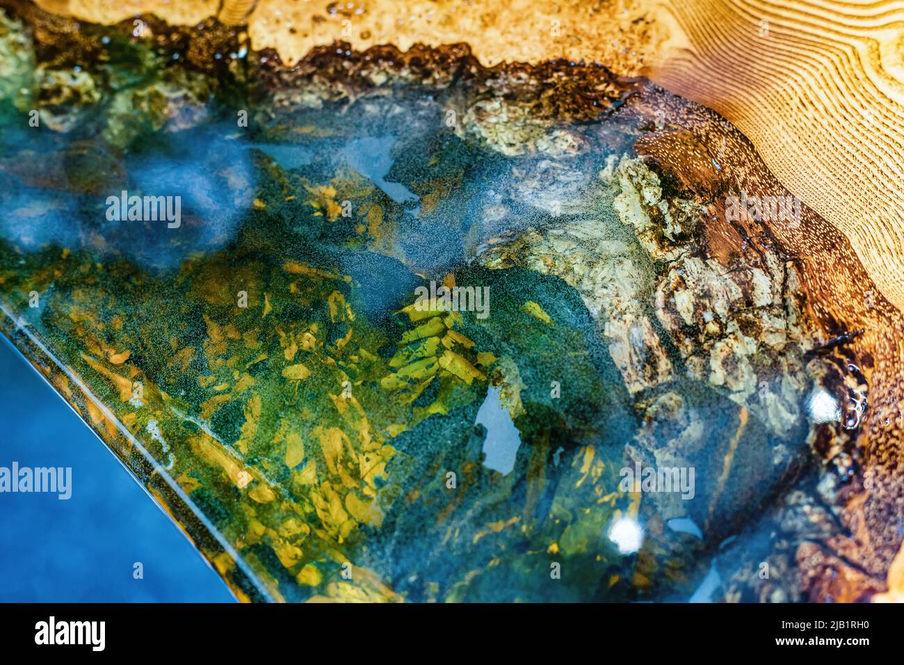 Tisch aus Epoxidharz mit transparenten Einsätzen und Holzsockel. Stockfoto