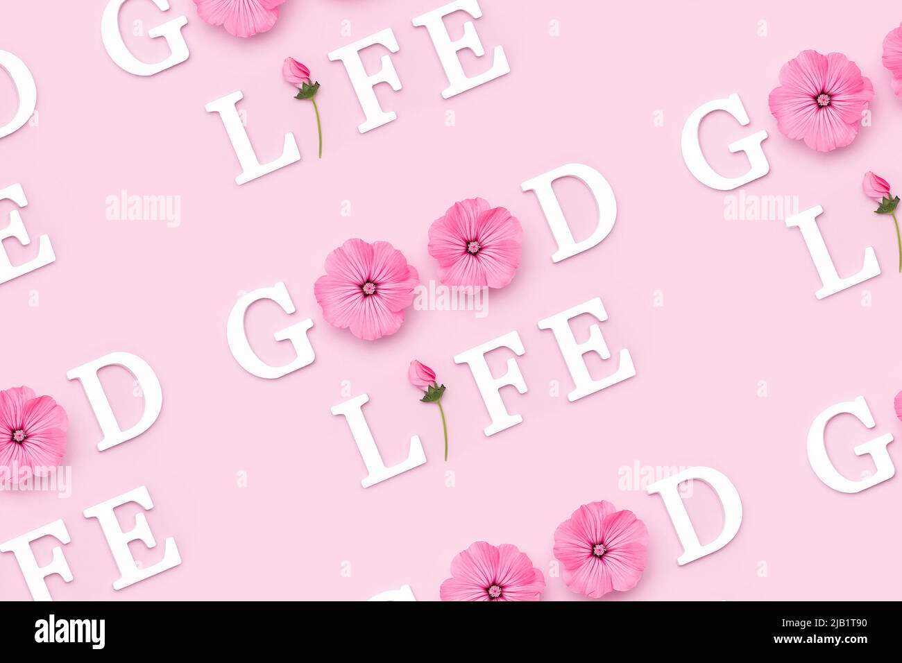 Gutes Leben. Kreatives inspirierendes Muster mit motivierenden Zitaten aus weißen Buchstaben und natürlichen Blumen auf rosa Hintergrund. Stockfoto