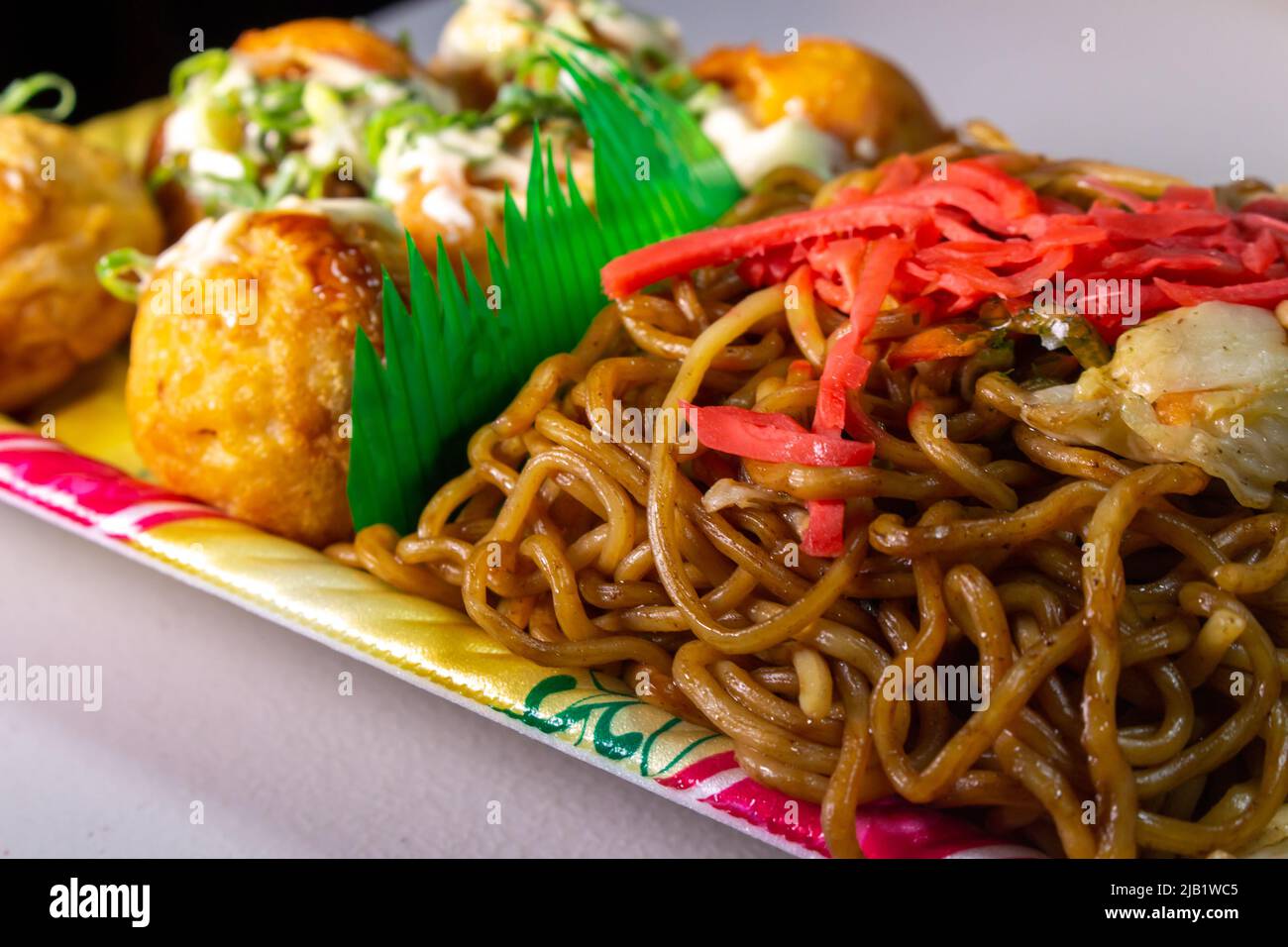 Japanisches traditionelles Street Food Yakisoba (gebratene Nudel) und Takoyaki (Krakenbälle) mit Mayonnaise-Sauce in einem Tablett, das vom japanischen Supermarkt verkauft wird. Stockfoto