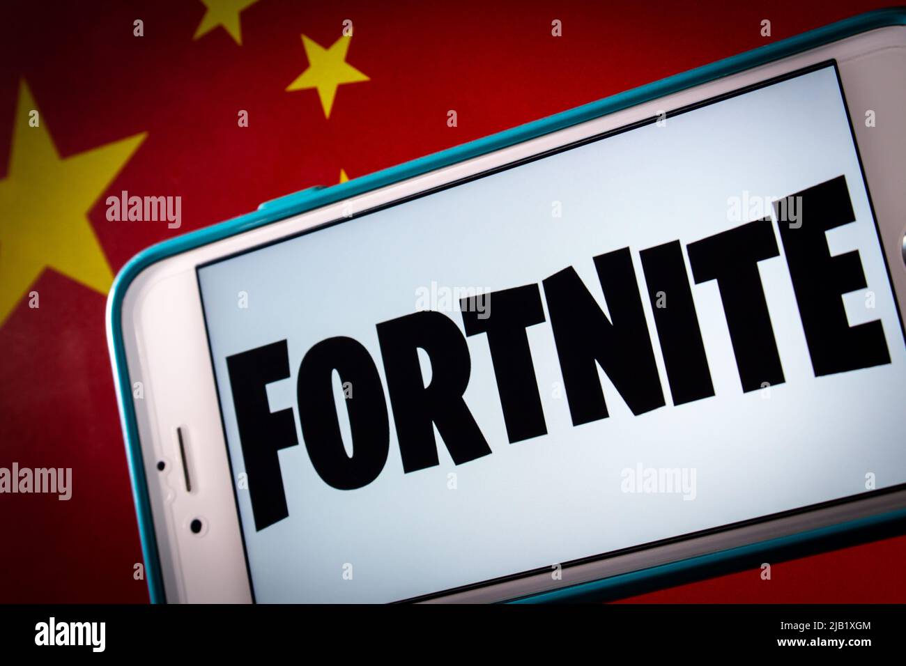 Kumamoto, JAPAN - Nov 9 2021 : Conceptual closeup Logo von Fortnit, Online-Videospiel entwickelt von Epic Games, auf iPhone auf chinesischer Flagge in dunkler Stimmung Stockfoto