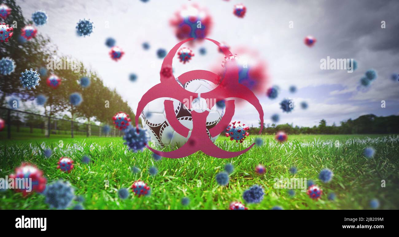 Biohazard-Symbol und Covid-19-Zellen gegen Fußball auf Sportplatz Stockfoto