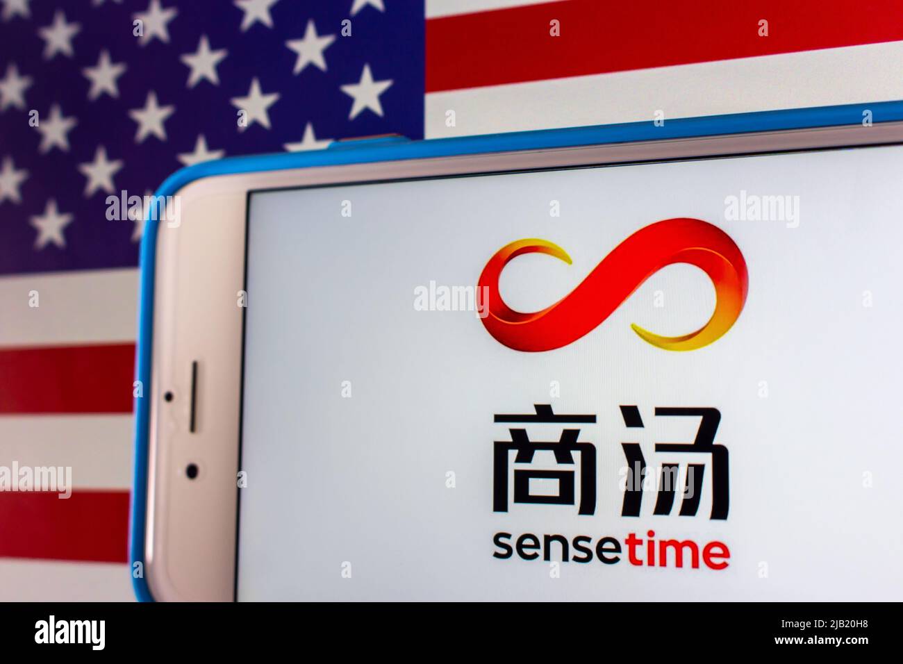 Kumamoto, JAPAN - Dez 14 2021 : das Logo von SenseTime, einem führenden Softwareunternehmen für künstliche Intelligenz mit Sitz in Hongkong, auf dem iPhone auf US-Flagge Stockfoto