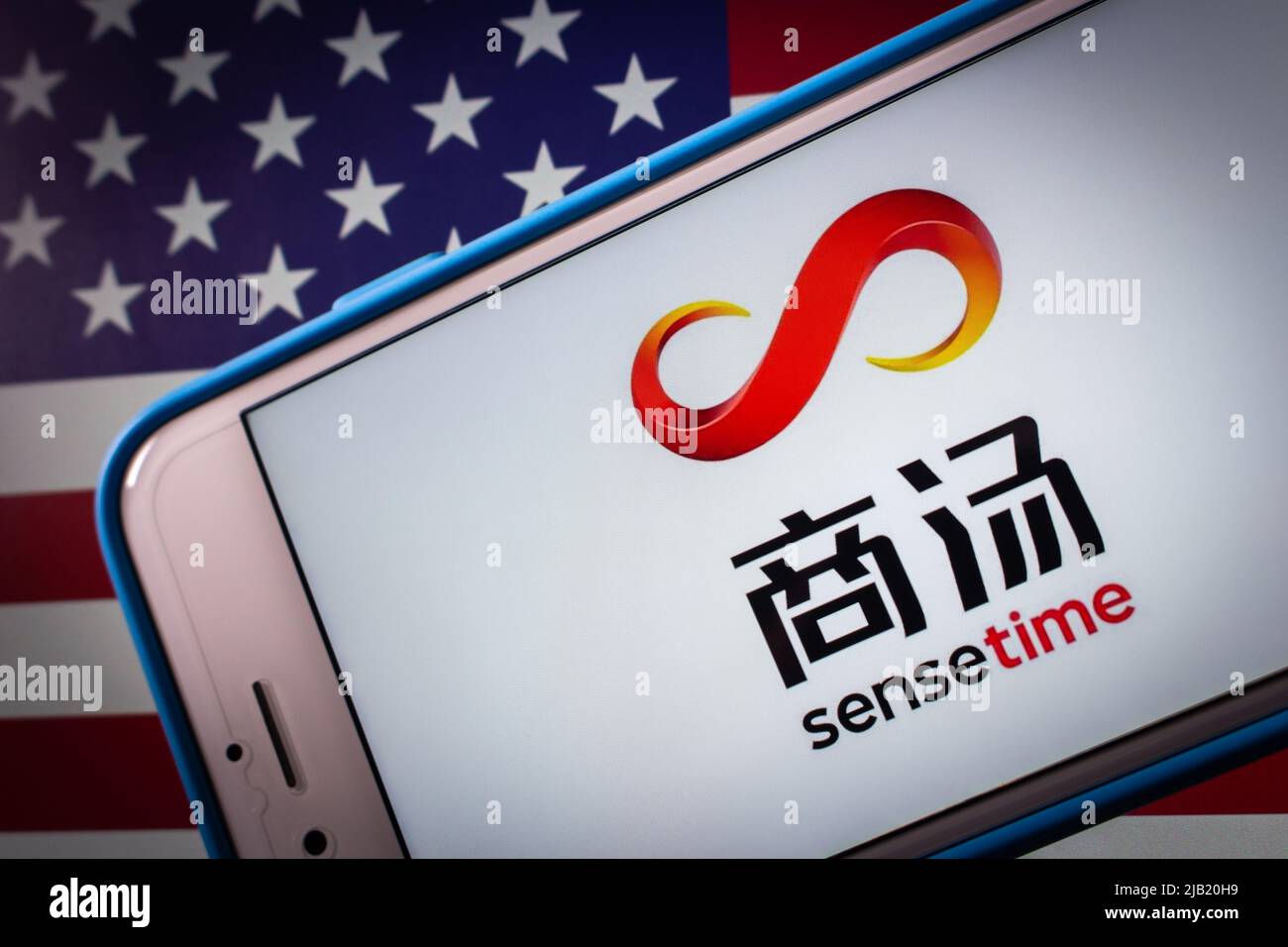 Kumamoto, JAPAN - Dez 14 2021 : Logo von SenseTime, einem führenden Softwareunternehmen für künstliche Intelligenz in Hongkong, auf dem iPhone auf US-Flagge in dunkler Stimmung Stockfoto