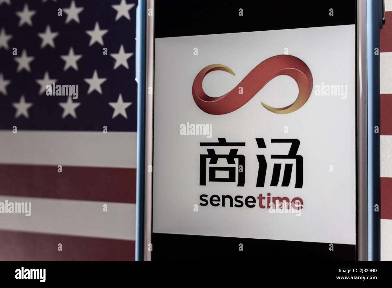 Kumamoto, JAPAN - Dez 14 2021 : Logo von SenseTime, einem führenden Softwareunternehmen für künstliche Intelligenz in Hongkong, auf dem iPhone auf US-Flagge in dunkler Stimmung Stockfoto