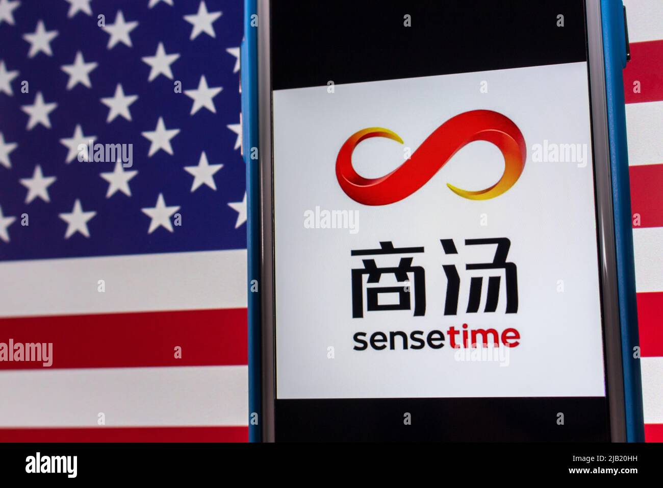 Kumamoto, JAPAN - Dez 14 2021 : das Logo von SenseTime, einem führenden Softwareunternehmen für künstliche Intelligenz mit Sitz in Hongkong, auf dem iPhone auf US-Flagge Stockfoto
