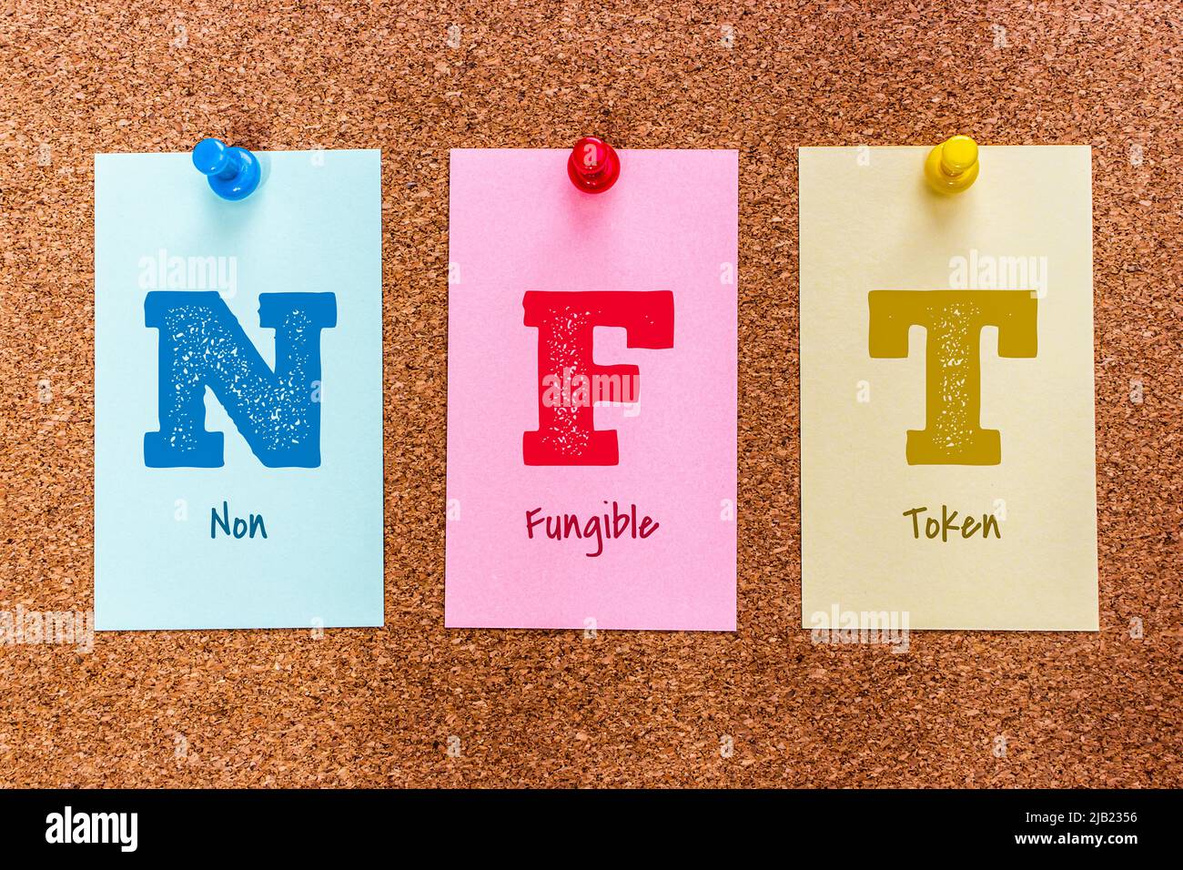 Concept 3 Buchstaben Schlüsselwort NFT (Ein nicht-fungible Token) auf bunten Aufklebern an einem Korkbrett befestigt. Stockfoto
