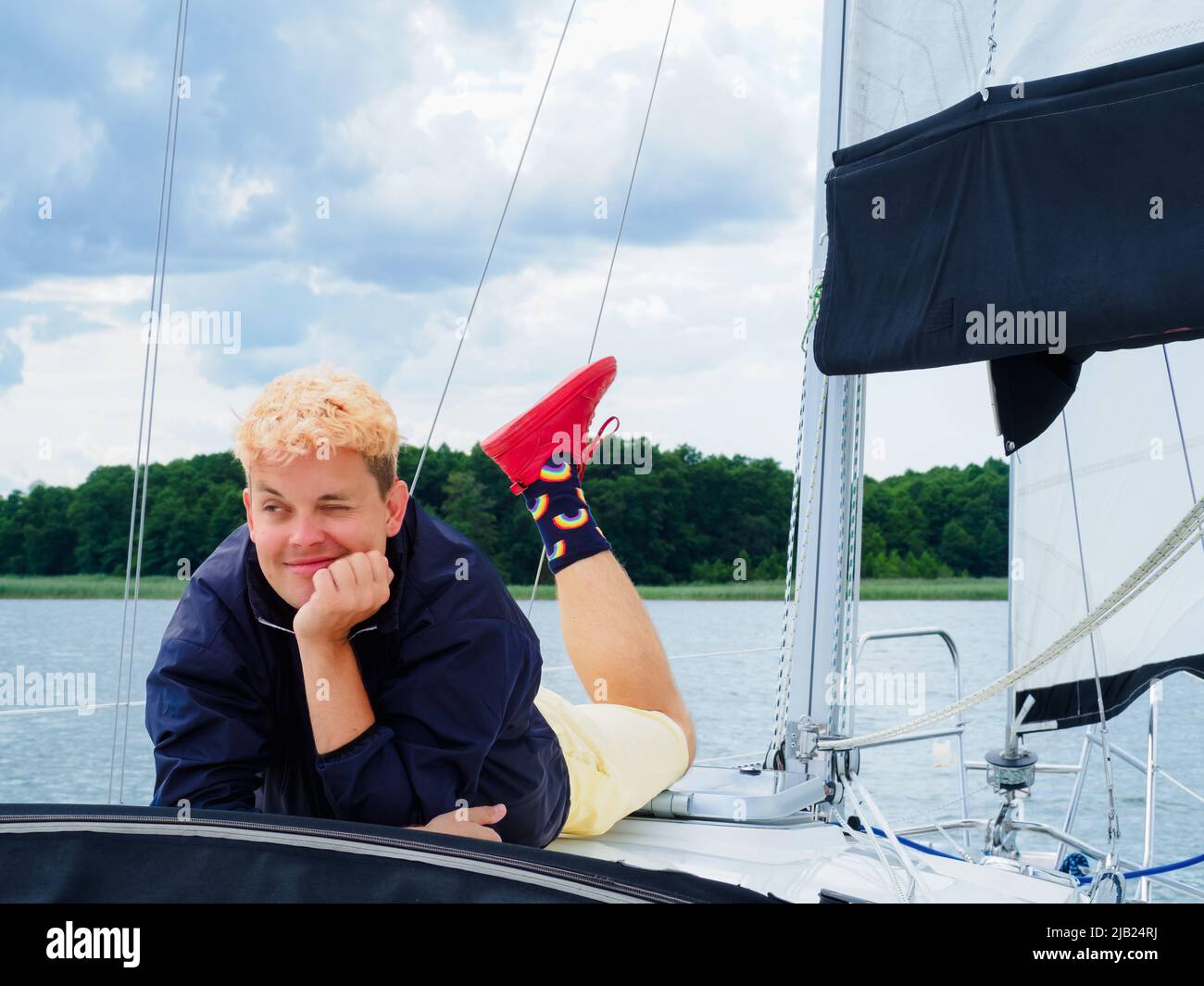 Gutaussehende Person, die auf dem Yacht-Deck liegt und auf einer Segelyacht in den Sommerferien genießt Stockfoto