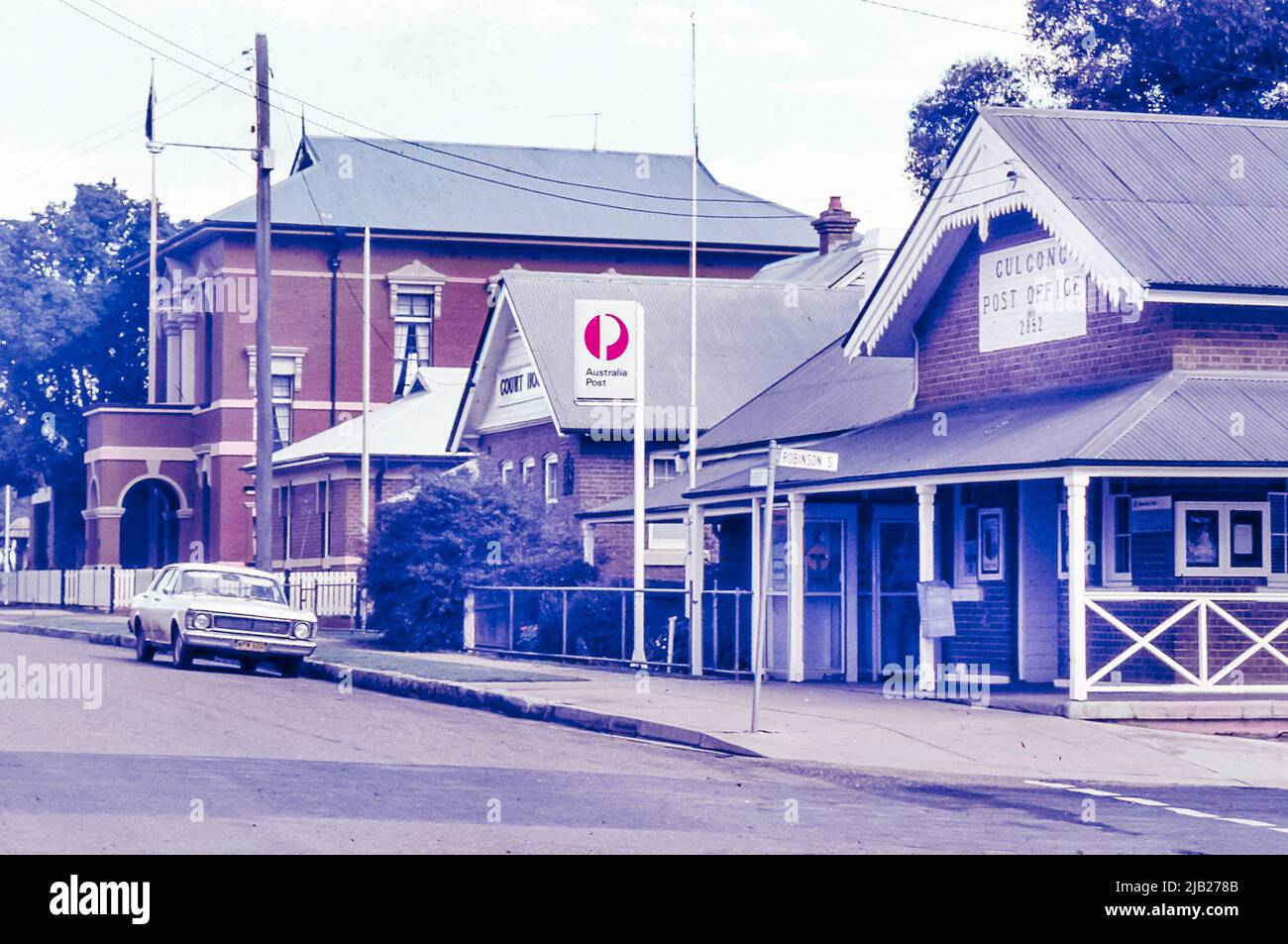 Eine 1985-farbige Folie des Postamtes, des Gerichtsgebäudes und der ehemaligen Gebäude des Ulan County Council in der Herbert Street, Gulgong, New South Wales, Australien. Ebenfalls zu sehen ist ein XW Ford Falcon, der in der typisch breiten County Street geparkt ist Stockfoto