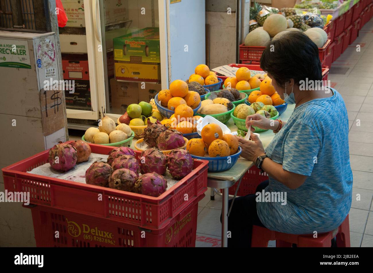 Frau, die Produkte arrangiert, zum Verkauf auf dem Markt in Tiong Bahru, Singapur Stockfoto