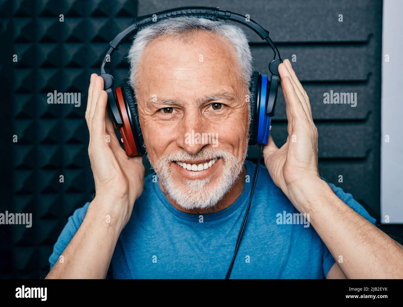 Behandlung von Hörverlust. Positiver älterer Mann, der Audiometriekopfhörer während des Hörtests und Audiogramms in einem speziellen Audioraum trägt Stockfoto