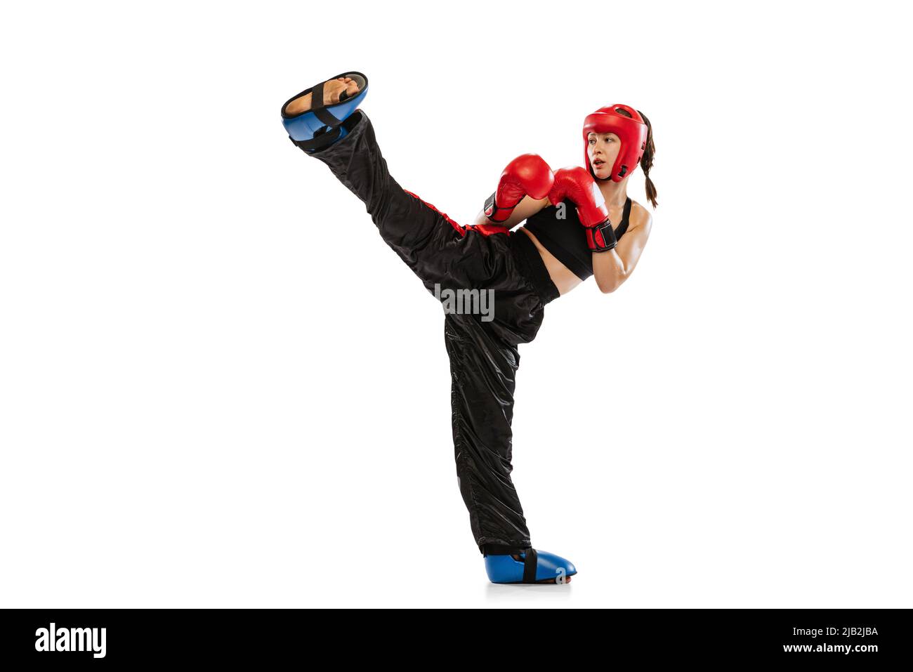 Hoher Kick. Eine Boxerin in Boxhandschuhen und Helmtraining isoliert auf weißem Studiohintergrund. Sport, Wettbewerb, Hobby, Ergebnisse, Erfolg Stockfoto