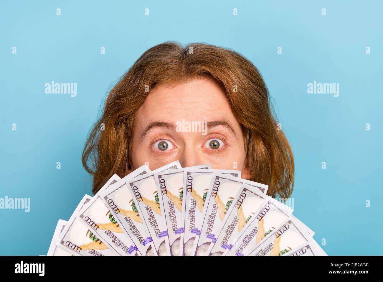 Portrait von attraktiven funky erstaunt Kerl versteckt Gesicht uns Dollar 100 atm Gehalt Budget isoliert über pastellblauen Hintergrund Stockfoto