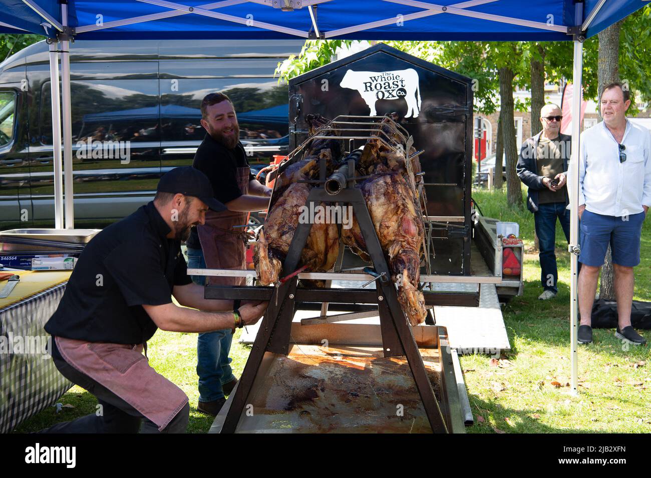 Windsor, Großbritannien. 2.. Juni 2022. Der geröstete Ochse wird aus dem Bräter genommen. Ein von Ihrer Majestät der Königin gestifteter Ochse wurde heute in Batchelor's Acre gebraten. Menschen, die eine Eintrittskarte für den Ochsenbraten gekauft haben, erhielten ebenfalls eine Teilnahmebescheinigung. Die ersten Scheiben wurden von Sir James Perowne, Govenor von Windsor Castle, und dem Bürgermeister von Windsor und Maidenhead, Cllr Christine Bateson, geschnitten. Quelle: Maureen McLean/Alamy Live News Stockfoto