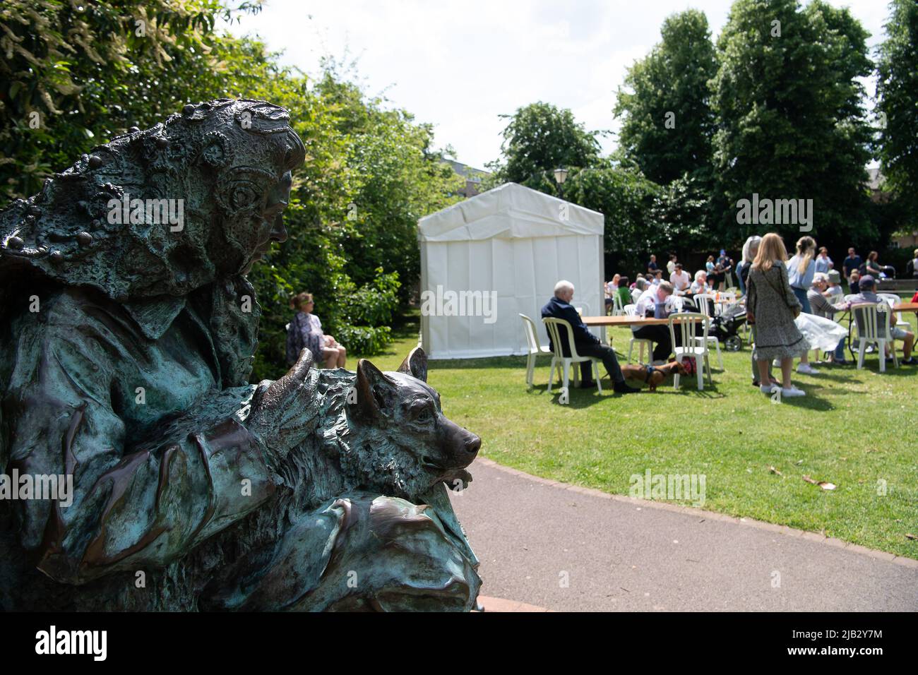 Windsor, Großbritannien. 2.. Juni 2022. Eine Bronzestatue von Königin Elizabeth II. Beobachtet das Ereignis. Ein von Ihrer Majestät der Königin gestifteter Ochse wurde heute in Batchelor's Acre gebraten. Menschen, die eine Eintrittskarte für den Ochsenbraten gekauft haben, erhielten ebenfalls eine Teilnahmebescheinigung. Die ersten Scheiben wurden von Sir James Perowne, Govenor von Windsor Castle, und dem Bürgermeister von Windsor und Maidenhead, Cllr Christine Bateson, geschnitten. Quelle: Maureen McLean/Alamy Live News Stockfoto