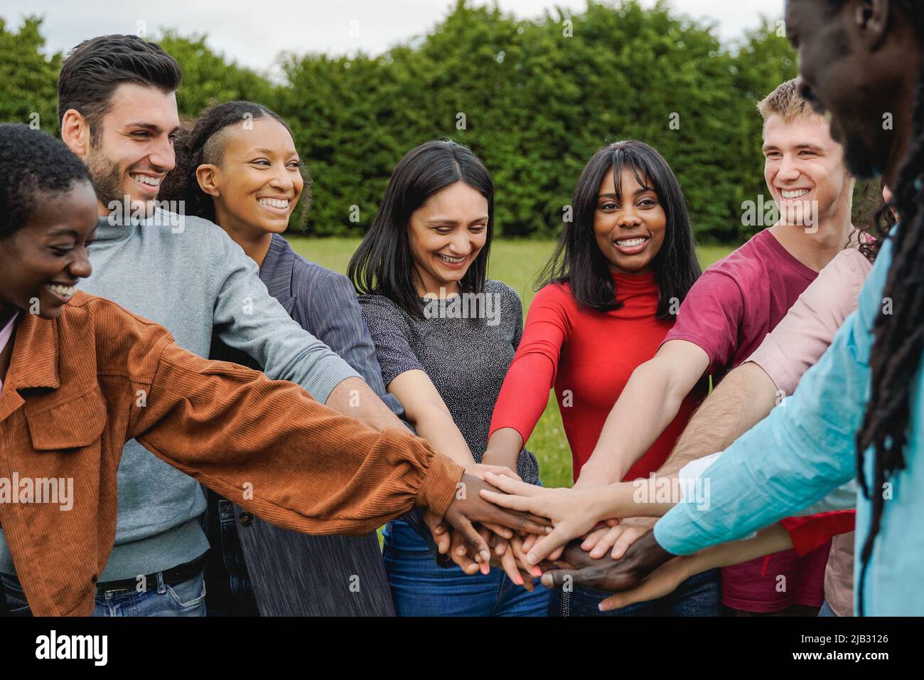 Junge, multiethnische Gruppe von Menschen, die ihre Hände im Freien stapeln - Konzept der Teamwork-Vielfalt und -Einheit Stockfoto