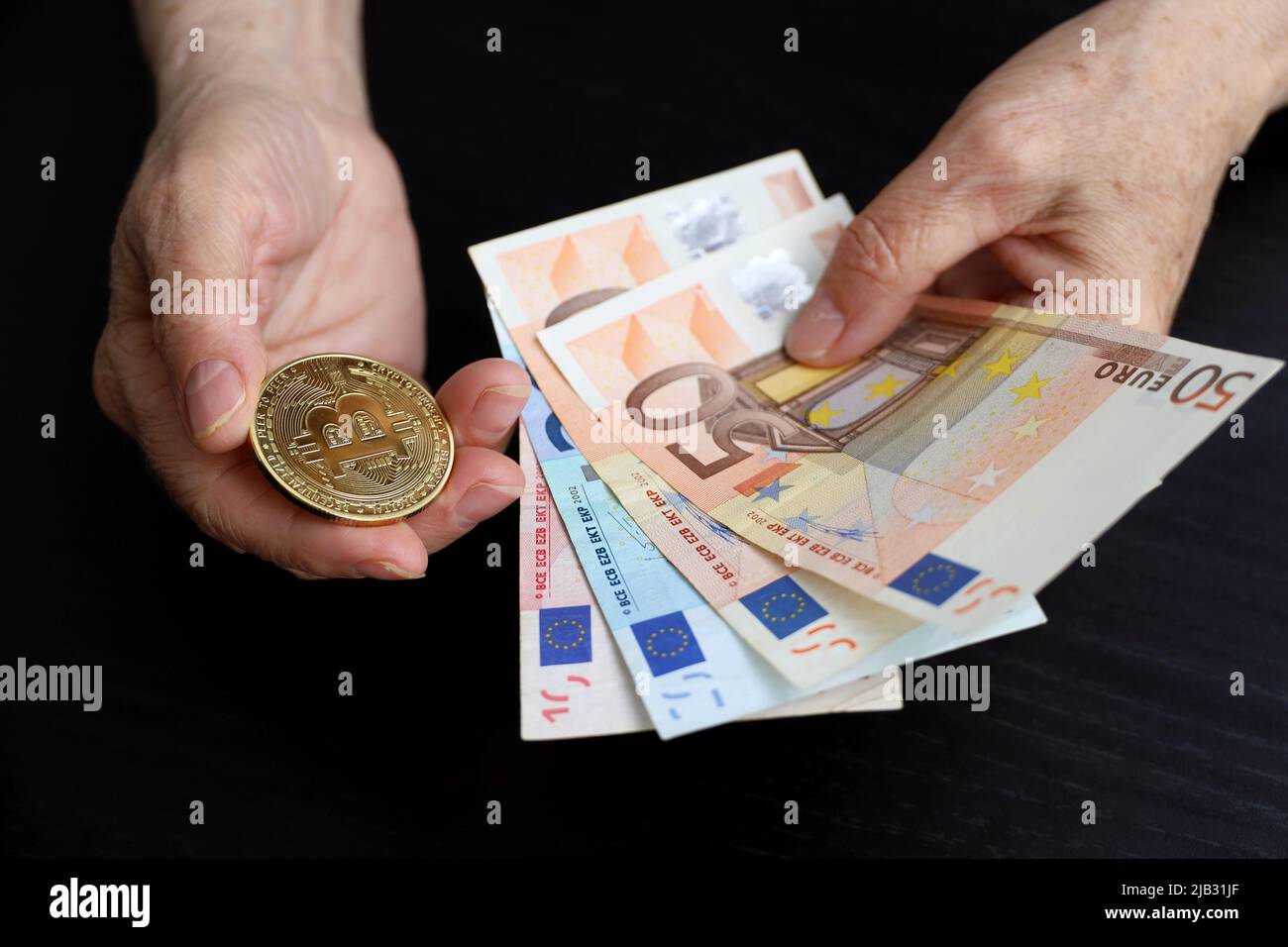 Bitcoin- und Euro-Banknoten in faltigen Händen älterer Frauen, Konzept der Altersvorsorge. Elektronisches dezentrales Geld, Kryptowährung Stockfoto