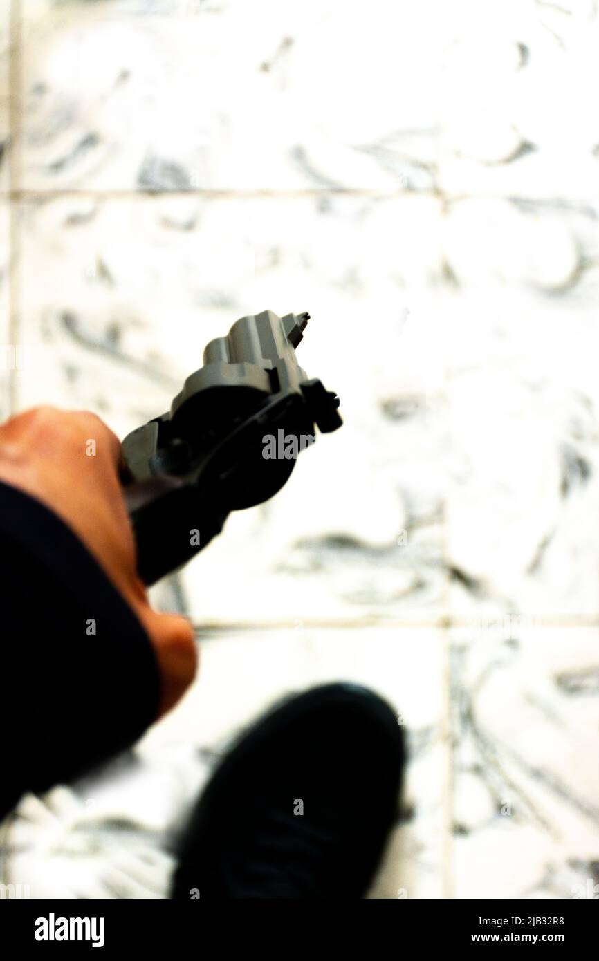 Hand mit einem Revolver mit selektivem Fokus und weißem Grund als Hintergrund. Konzepte wie Sicherheit, Selbstschutz oder kriminelle Handlung Stockfoto