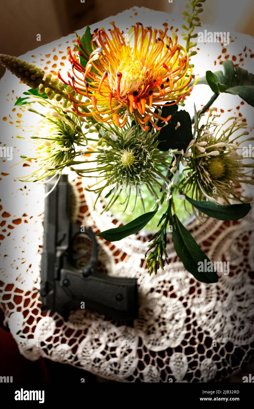 Gun aus dem Fokus auf einem Beistelltisch neben einer Vase mit Blumen. Konzept des Rechts auf Selbstschutz zu Hause oder Gewalt in der Familie Stockfoto
