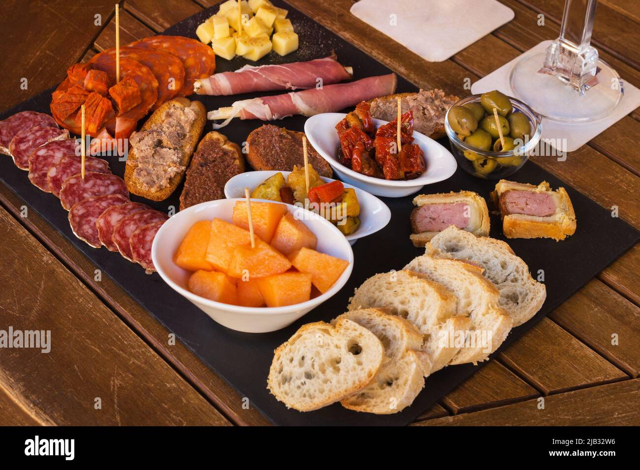 Wurst und Käse auf braunem Hintergrund in Scheiben geschnitten. Italienische Antipasti-Wein-Snacks. Käse, mediterrane Oliven, Prosciutto mit Melone, Brotstangen Stockfoto