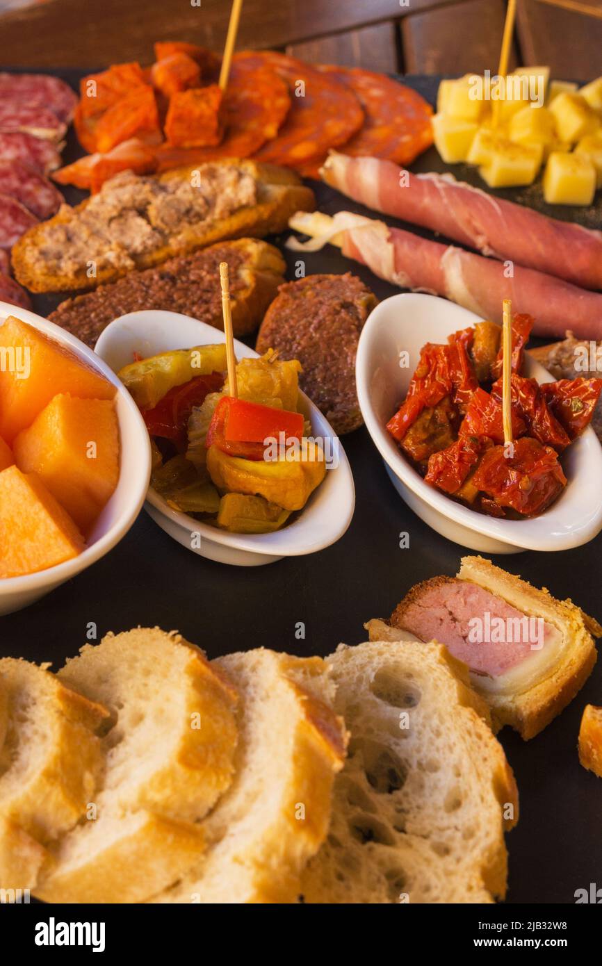 Wurst und Käse auf braunem Hintergrund in Scheiben geschnitten. Italienische Antipasti-Wein-Snacks. Käse, mediterrane Oliven, Prosciutto mit Melone, Brotstangen Stockfoto